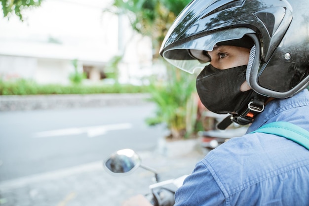 Primer plano de un hombre con casco en una motocicleta en el fondo de la calle de la ciudad