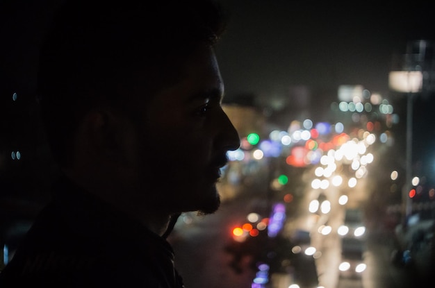 Foto primer plano de un hombre en una ciudad iluminada