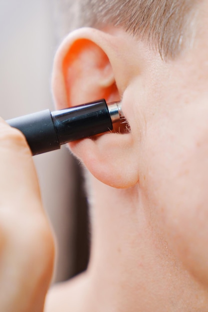 Primer plano, un hombre se corta el pelo de la oreja con una recortadora