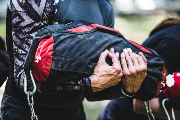 Primer plano del hombre entrenando en el centro de crossfit con bolsa de arena.