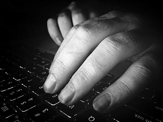 Primer plano de un hombre escribiendo en una computadora portátil