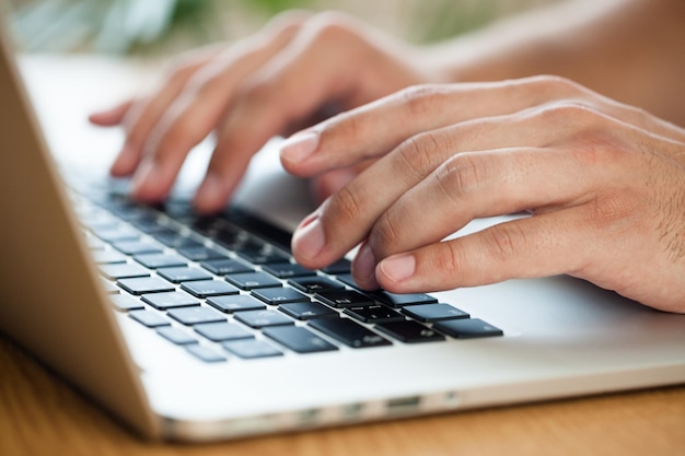 Primer plano de un hombre escribiendo en una computadora portátil