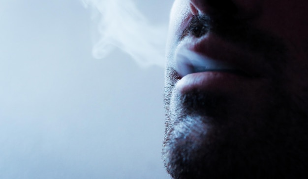 Primer plano de un hombre exhalando humo