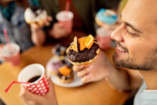 Primer plano de hombre feliz comiendo donut de chocolate para el postre