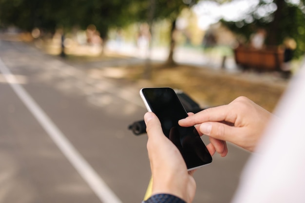 Primer plano de un hombre hambriento que usa el teléfono durante el descanso antes de montar en escooter