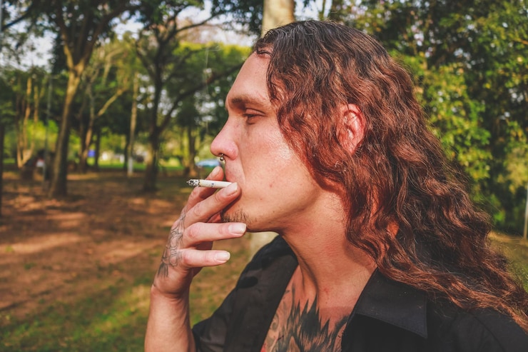 Foto primer plano de un hombre hipster fumando en el parque
