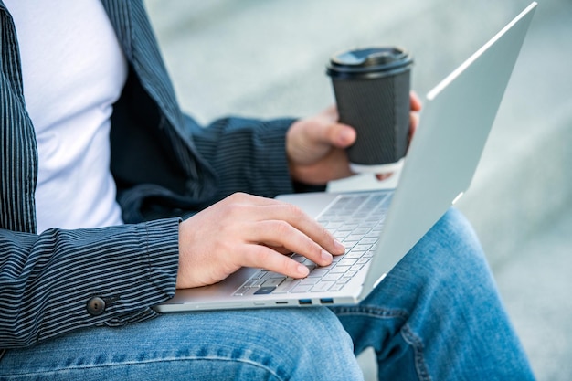 Primer plano de un hombre independiente con café escribiendo comunicación en línea en línea de un hombre independiente