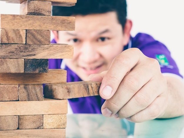 Primer plano de un hombre jugando a un juego de eliminación de bloques en una mesa contra un fondo blanco