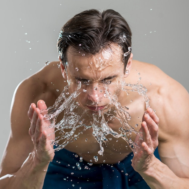 Foto primer plano de hombre lavándose la cara con agua