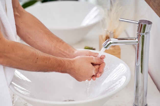 Primer plano del hombre lavándose las manos en el baño por la mañana