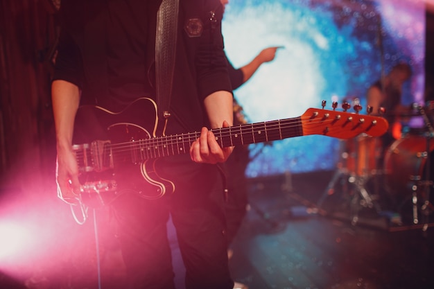 Foto primer plano de un hombre manos rasgueando la guitarra eléctrica