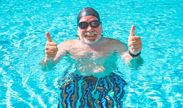 Primer plano de un hombre mayor sonriente haciendo deporte y nadar en la piscina