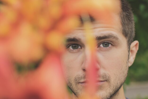 Foto primer plano de un hombre mirando a través de flores de naranja