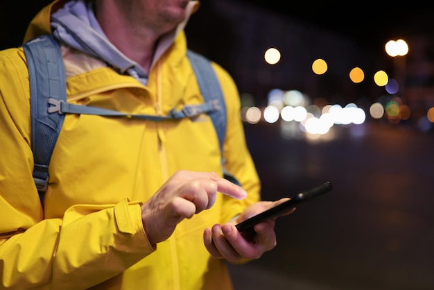 Primer plano de hombre con mochila mirando su teléfono móvil al aire libre encontrar comunicación