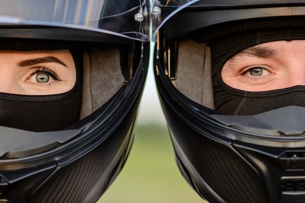 Un primer plano de un hombre y una mujer con cascos de motocicleta apoyados uno contra el otro