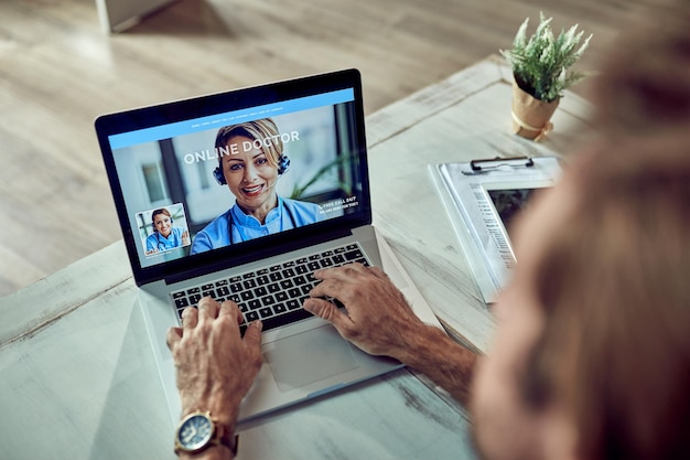 Primer plano de un hombre de negocios comunicándose con un médico a través de una computadora portátil desde su oficina El foco está en la pantalla de la computadora portátil