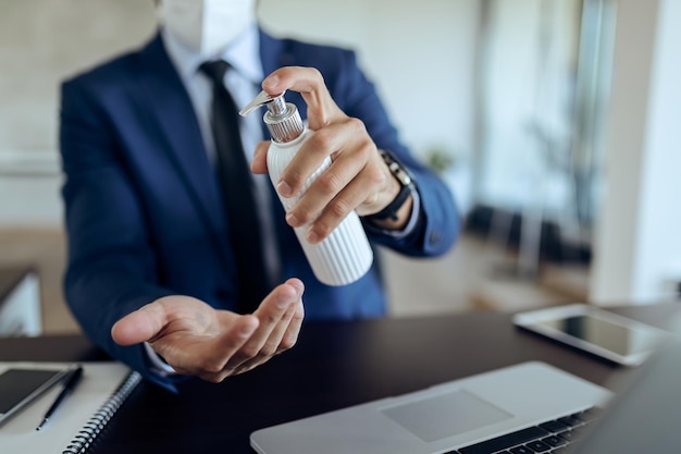 Primer plano de un hombre de negocios desinfectando las manos en la oficina