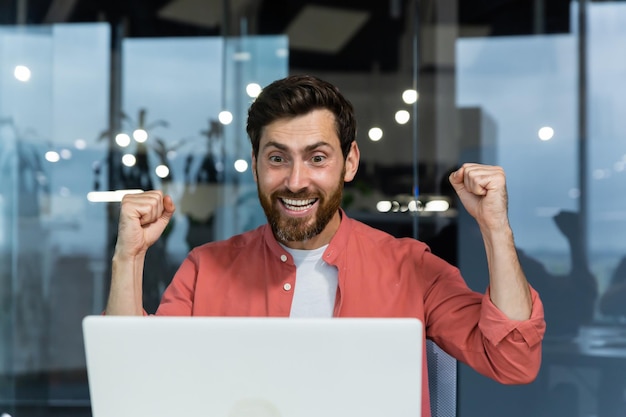 Foto primer plano de un hombre de negocios exitoso que celebra la victoria y el triunfo exitoso mirando la computadora portátil