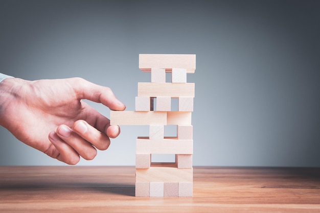 Primer plano de un hombre de negocios haciendo una estructura con cubos de madera Construyendo un concepto de negocio