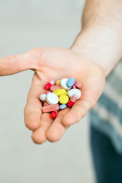 Primer plano de un hombre con pastillas de colores en su mano derecha