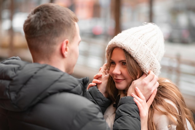 Primer plano de un hombre poniéndole un sombrero a su novia sonriente en la calle. Estilo de vida feliz de hombre y mujer. El concepto de día de san valentín ligero, regalos.