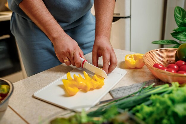 Primer plano del hombre preparando ensalada vegana de verduras en la cocina Estilo de vida de concepto de dieta y comida saludable Cocinar en casa