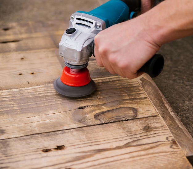 Primer plano de un hombre puliendo madera. Equipo para procesar tableros de madera. Superficie lisa y uniforme.