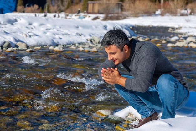 Primer plano de un hombre que se lava la cara con agua del río