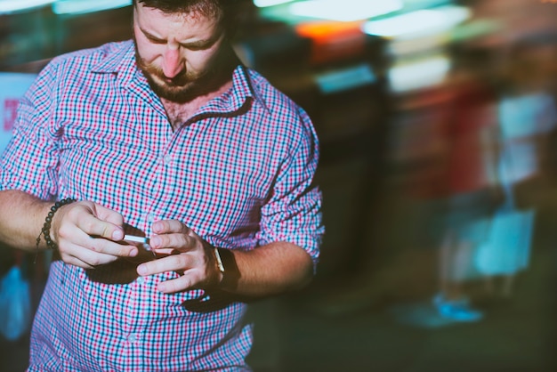 Primer plano de un hombre que usa el teléfono móvil en la oscuridad con luz de larga exposición