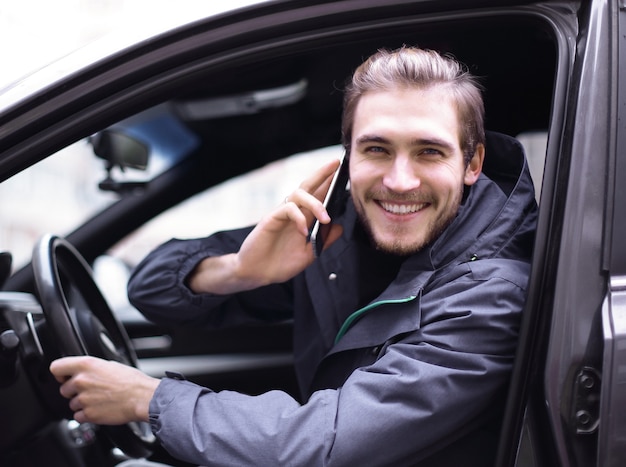 Foto primer plano. hombre sonriente hablando por teléfono móvil en el coche.