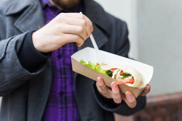 Primer plano del hombre sostiene sándwich de falafel en bolsa de papel. Concepto de comida callejera saludable, cocina oriental.