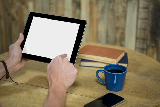 Primer plano del hombre con tableta digital con pantalla en blanco en la cafetería.