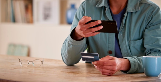 Primer plano del hombre con tarjeta de crédito en casa mediante teléfono móvil para comprobar las finanzas para iniciar un negocio