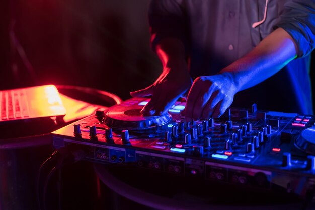 Primer plano de un hombre tocando música en un equipo de audio en un club nocturno