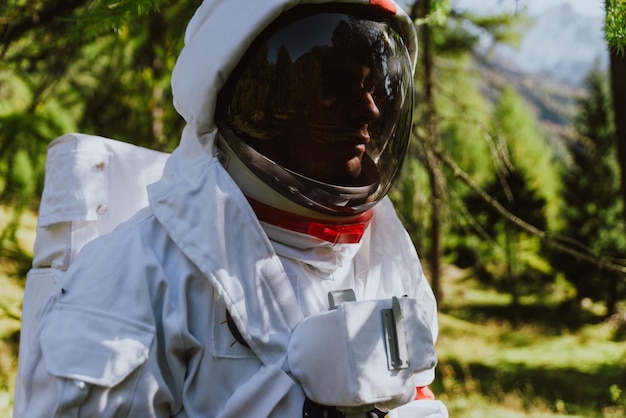 Primer plano de un hombre con traje espacial contra los árboles