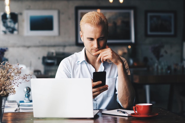 Primer plano de un hombre usando el teléfono móvil mientras está sentado en la mesa