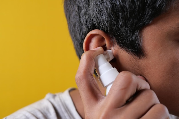 Primer plano de hombres que usan spray para eliminar el cerumen