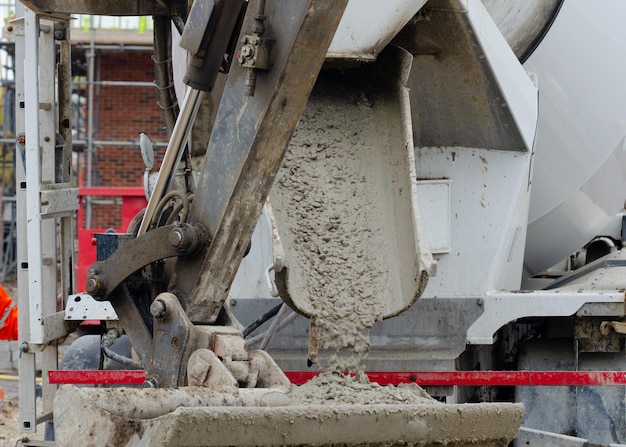 Primer plano de hormigón que fluye hacia el cucharón de la excavadora desde el vagón de entrega