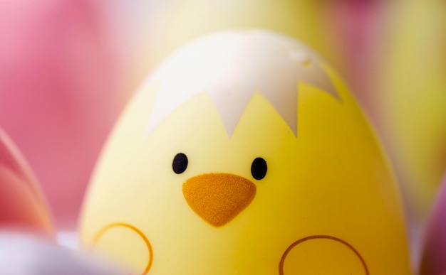Primer plano de huevo de Pascua amarillo con pollo en él contra un fondo rosado colorido