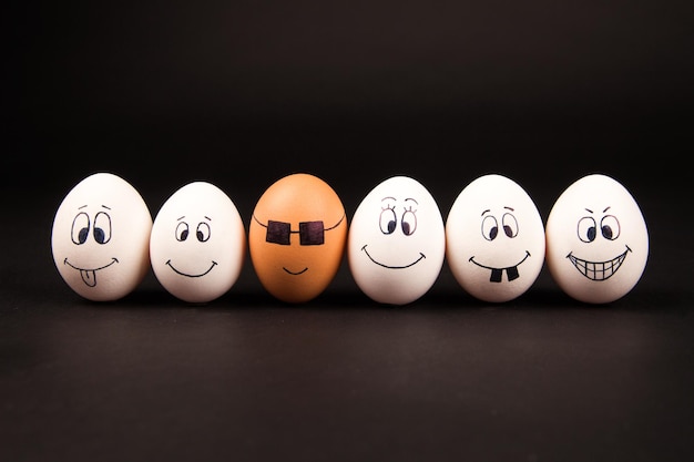Primer plano de huevos con cara antropomórfica dispuesta sobre un fondo negro.