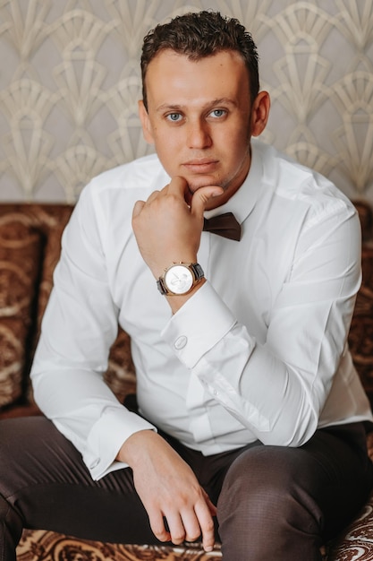 Foto primer plano de una imagen de moda de un reloj de lujo en la ciudad detalle del cuerpo de un hombre de negocios mano de hombre en pantalones marrones bolsillo primer plano en fondo gris un hombre con pantalón marrón y una camisa blanca
