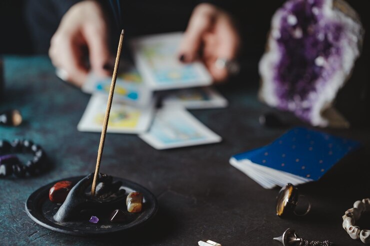 Foto primer plano de incienso con una mujer sosteniendo una carta de tarot en la mesa