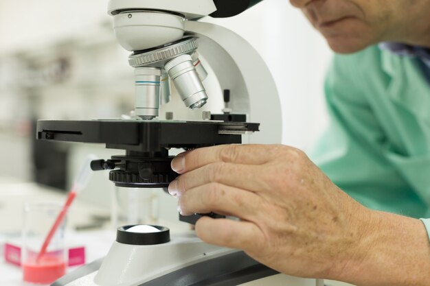 Primer plano de un investigador científico masculino con microscopio en el laboratorio.