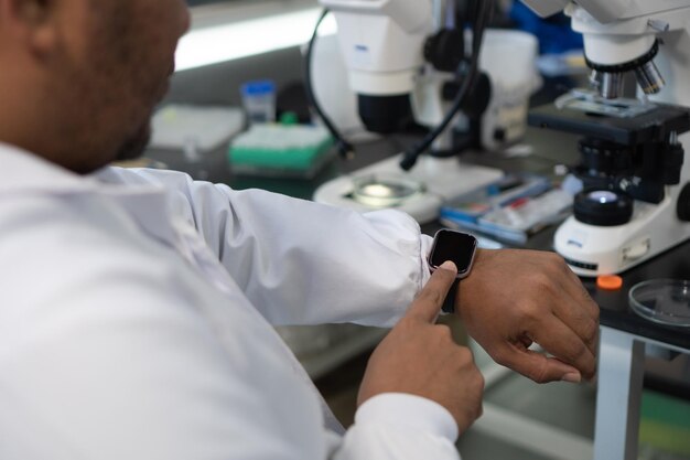 Primer plano de un investigador que usa un reloj inteligente en un laboratorio