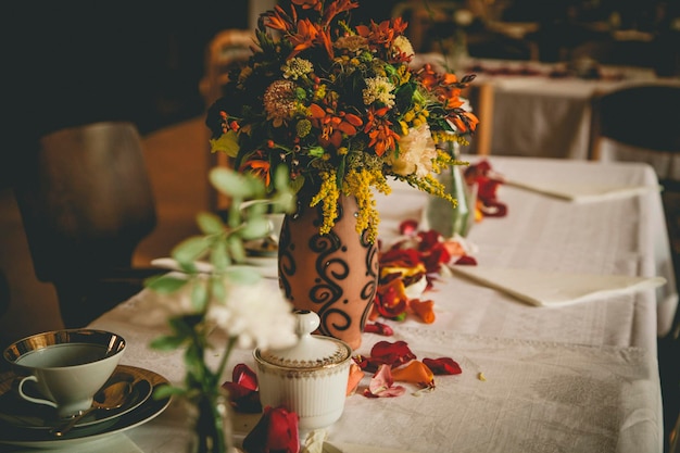 Primer plano de un jarrón de flores en una mesa decorada