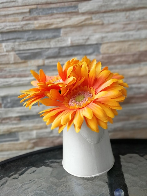 Primer plano de un jarrón de flores de naranja en la mesa