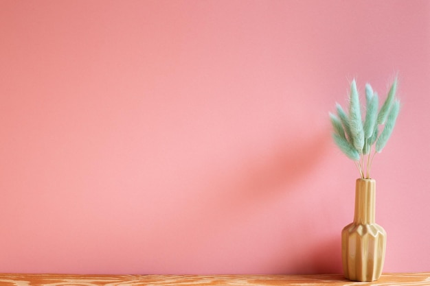 Primer plano de un jarrón de flores rosas contra la pared