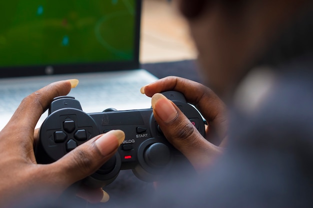 Primer plano de un joven africano sosteniendo game pad, pad de consola mientras juega