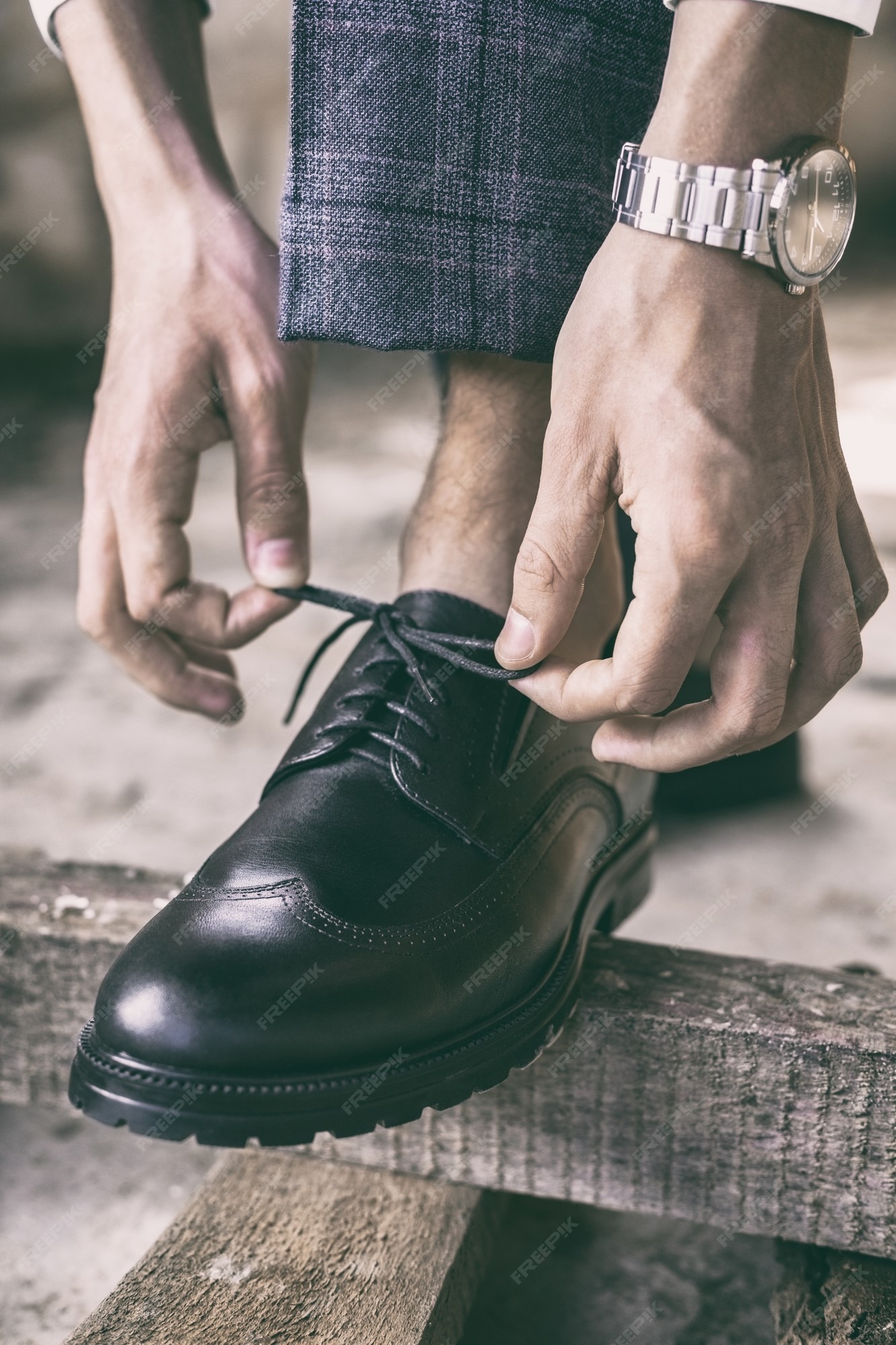 Primer plano joven ata sus cordones en elegantes zapatos negros, imagen tonificada | Foto