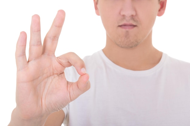 Primer plano de un joven atractivo que muestra un signo bien aislado de fondo blanco